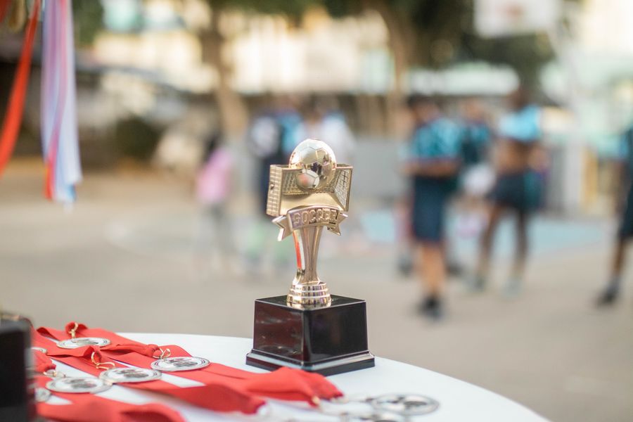 A close-up of a polished silver soccer trophy with medals