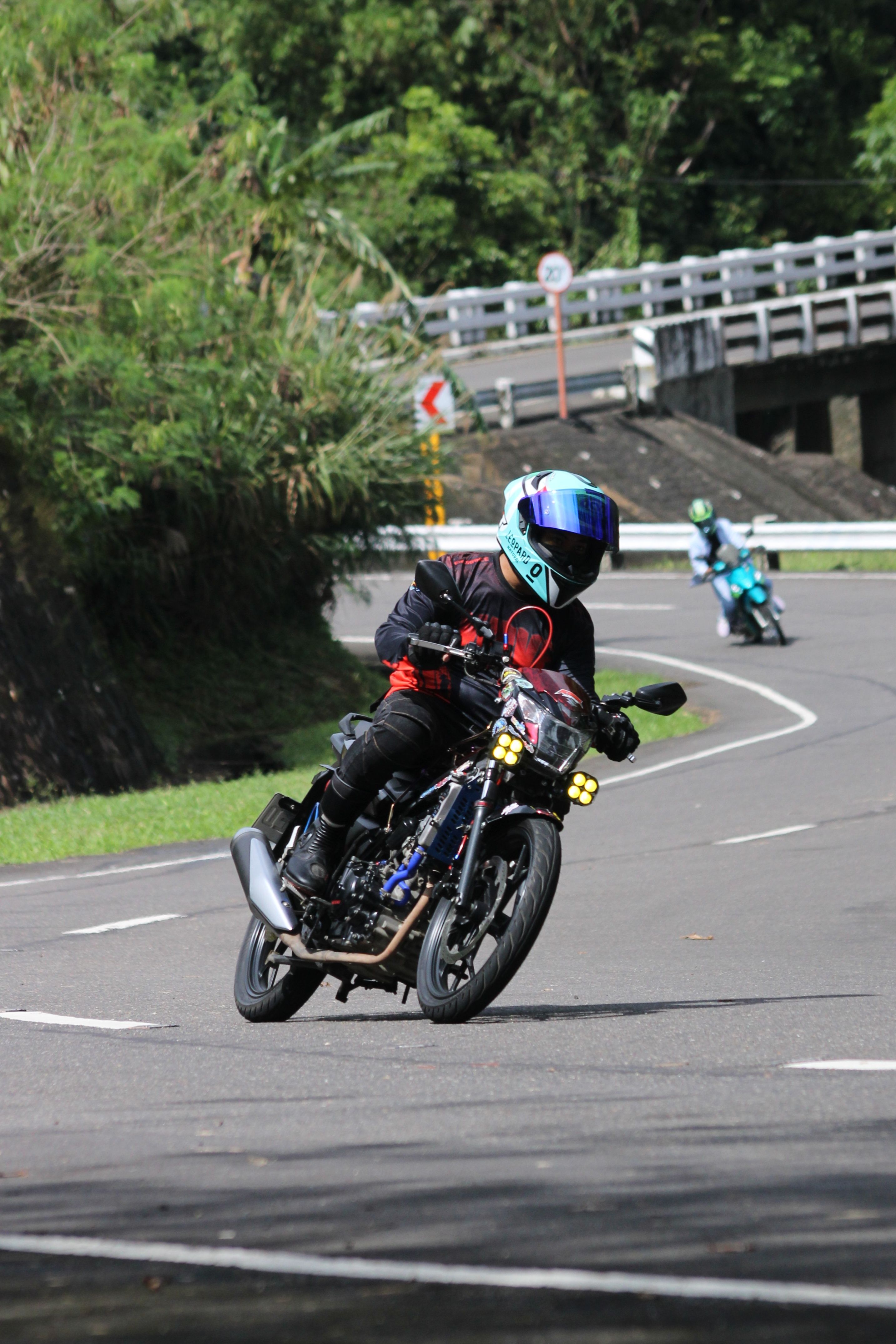 A motorcyclist in full gear navigating a curvy road during the day.