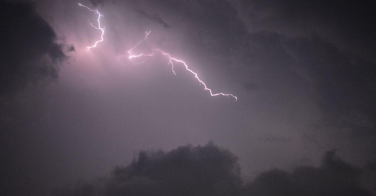 Photo by Nishant Mittal A striking bolt of lightning illuminates the stormy night sky above dark clouds.