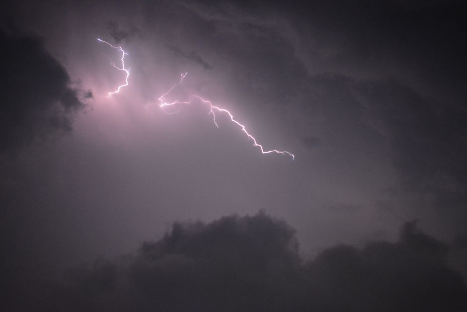 Photo by Nishant Mittal A striking bolt of lightning illuminates the stormy night sky above dark clouds.