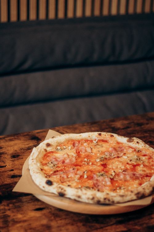 Free Delicious Neapolitan pizza with tomatoes and cheese on a rustic wooden table. Stock Photo