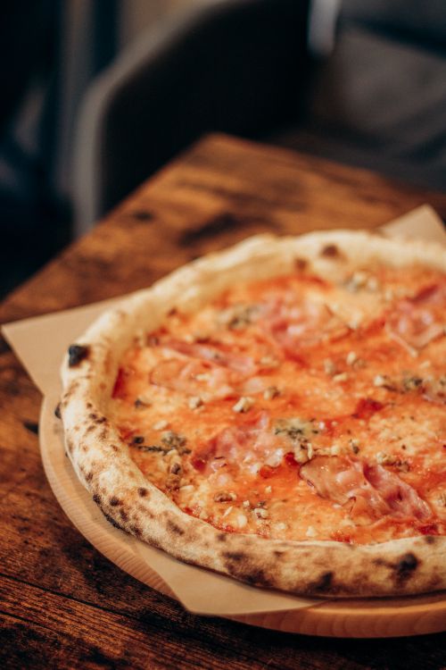 Free Mouth-watering Italian pizza with prosciutto and cheese served on a rustic wooden table. Stock Photo