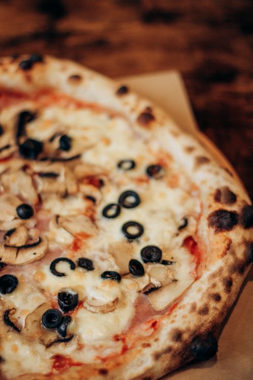 Free Tasty pizza topped with mushrooms, olives, and cheese. Ideal for food blogs and culinary websites. Stock Photo