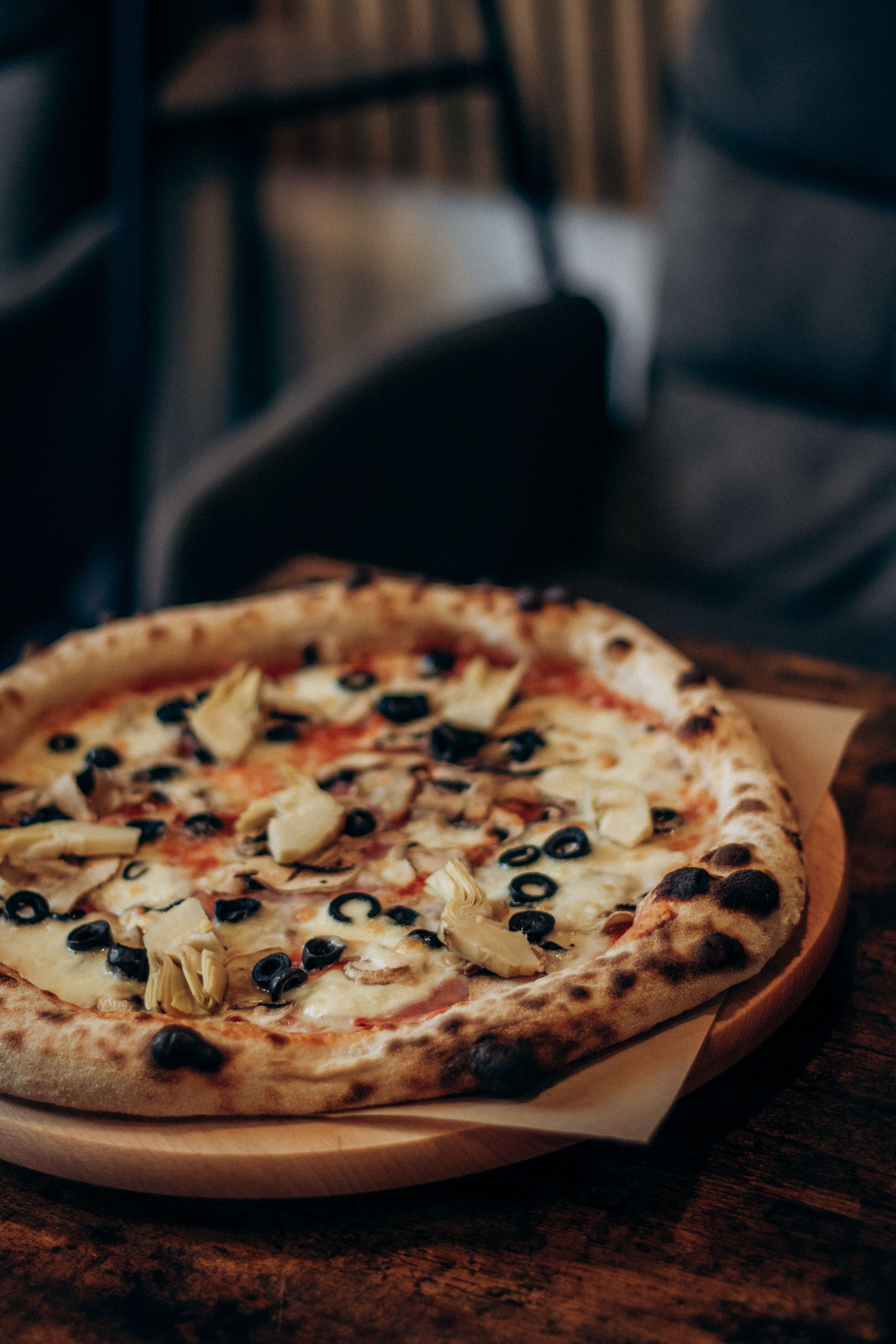 Close-up of a delicious artisan pizza topped with olives, artichokes, and cheese, ideal for food lovers.