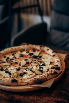Close-up of a delicious artisan pizza topped with olives, artichokes, and cheese, ideal for food lovers.