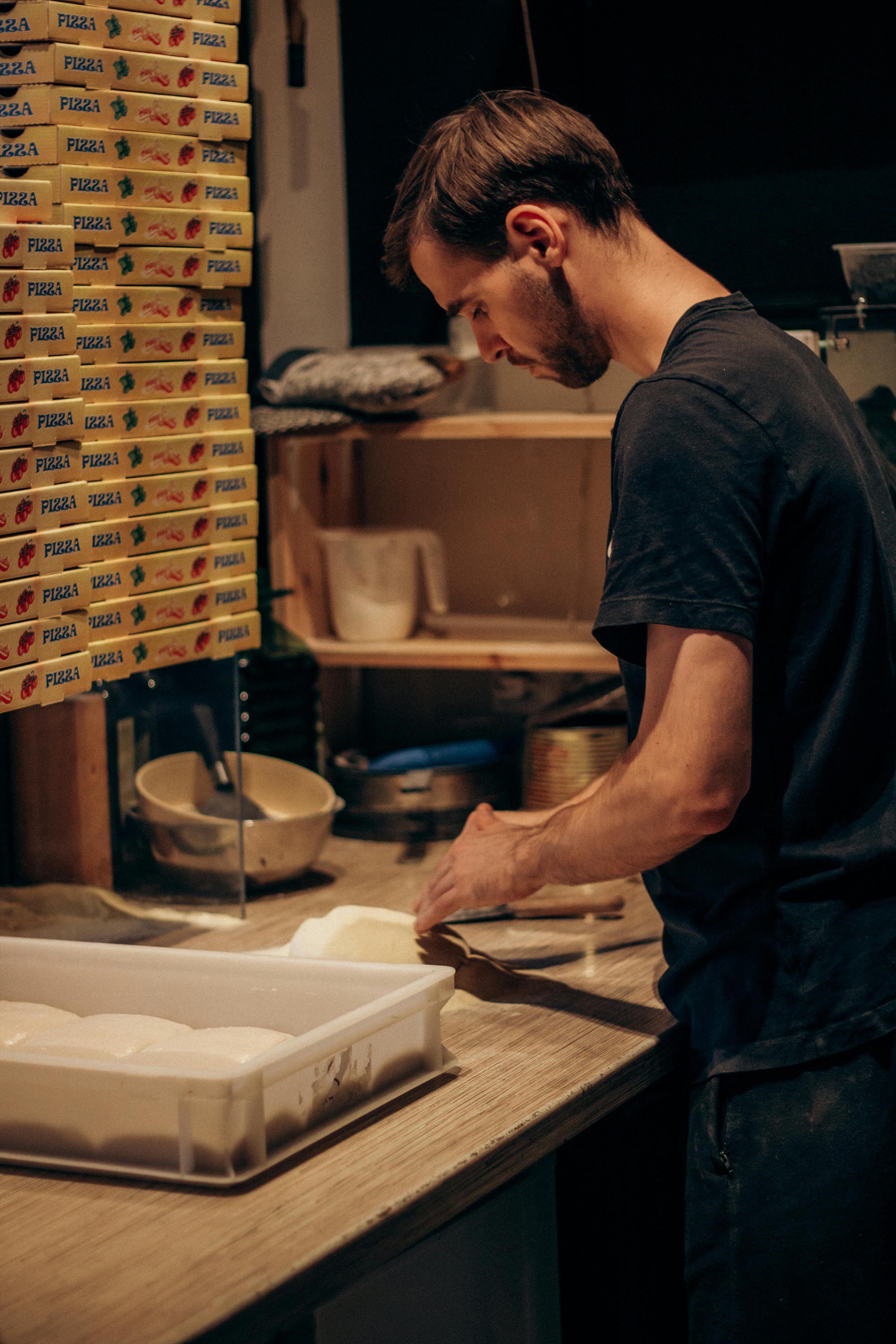 Skilled chef preparing pizza dough in a cozy kitchen setting.