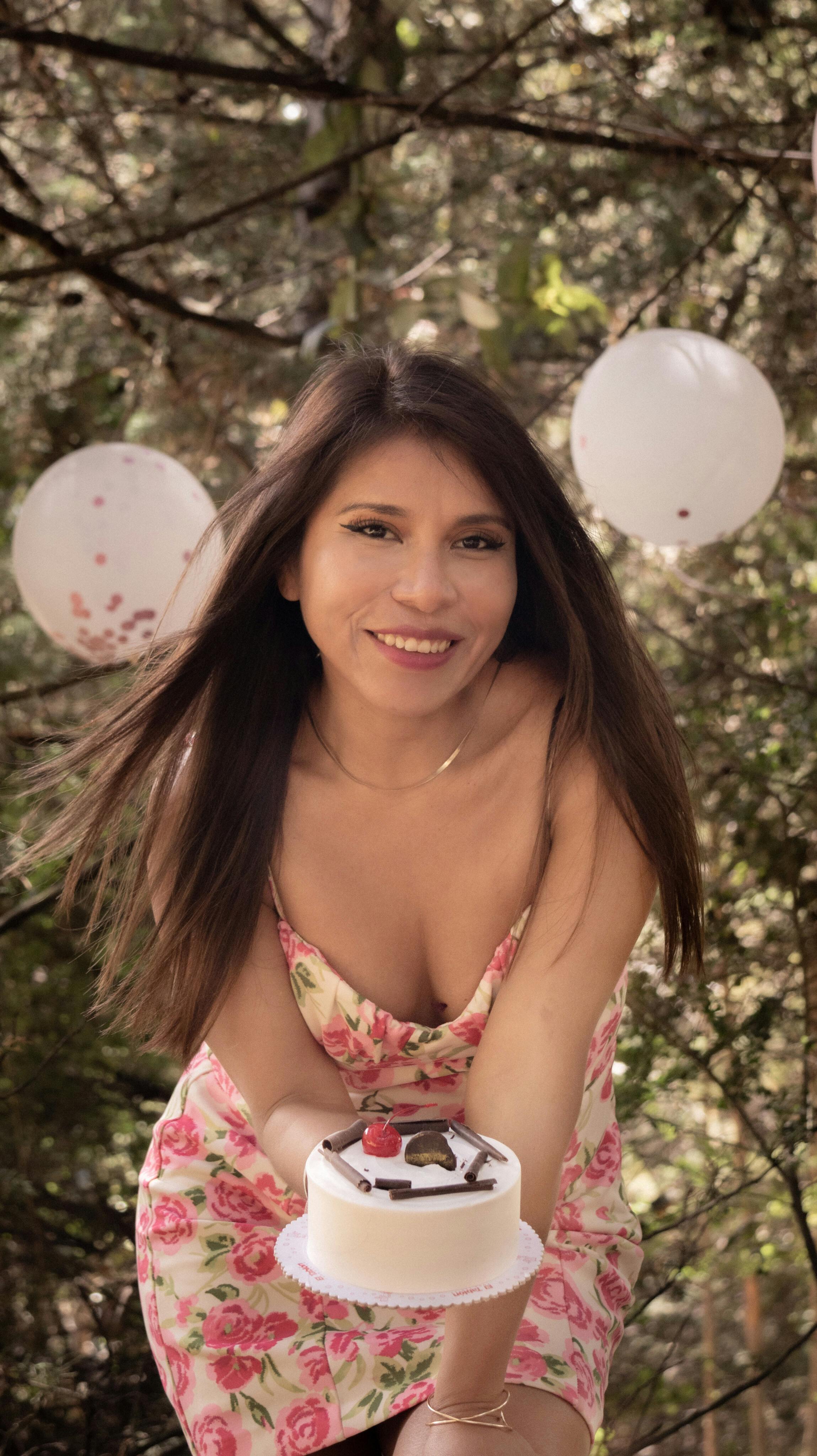 무료 숲 속에서 풍선이 달린 생일 케이크를 들고 웃는 여자. 스톡 사진