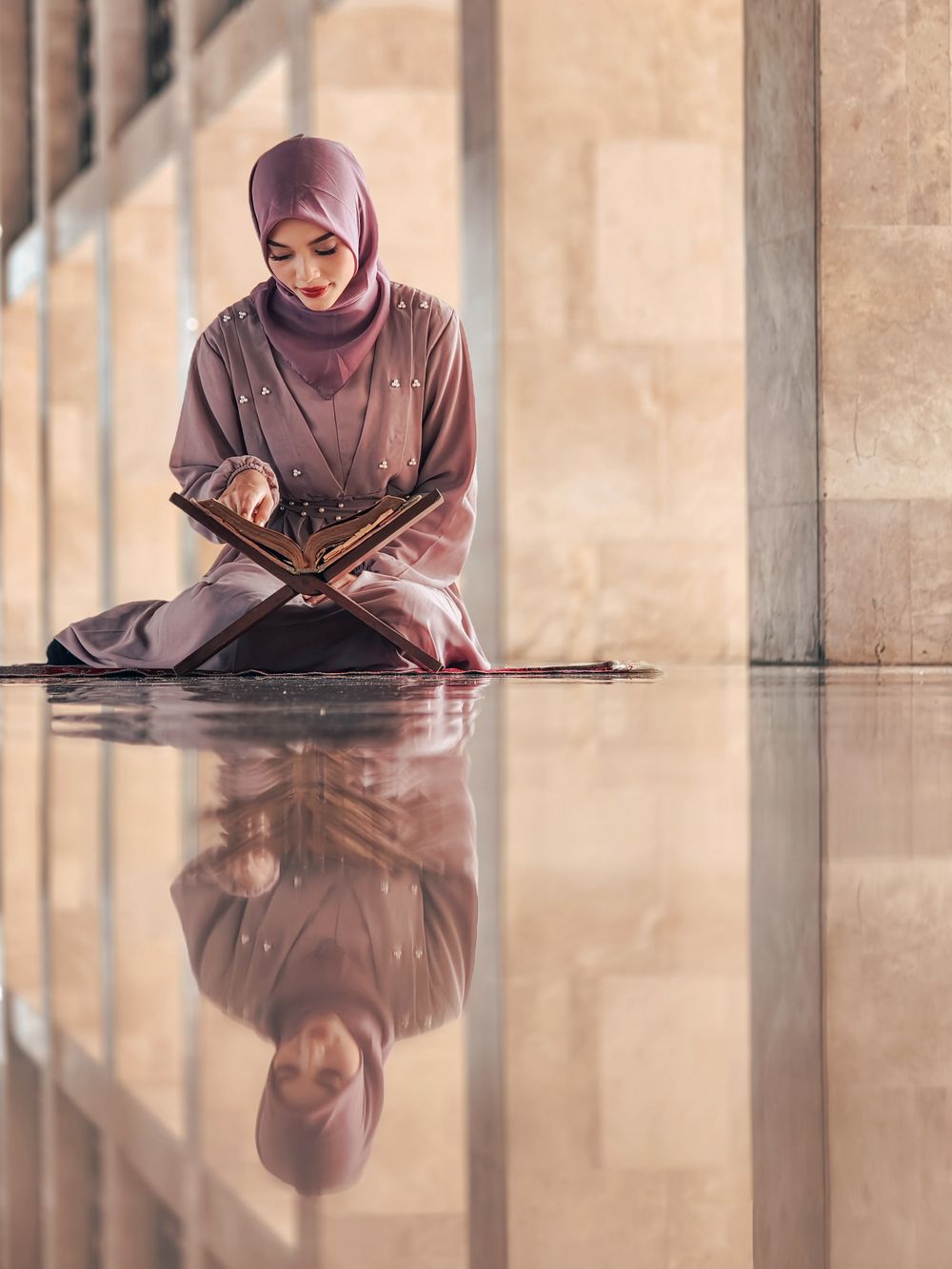 Woman in hijab reading the Quran in a peaceful indoor setting
