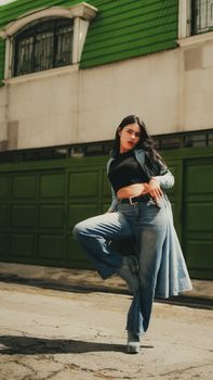 Fashionable woman in denim outfit striking a pose on an urban street.