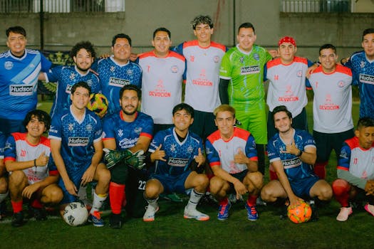 A group of amateur soccer players posing on a field with various team jerseys.