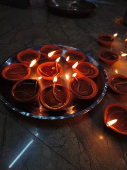 Clay diyas with glowing flames set on a tray, capturing the warm ambiance of a festival celebration.
