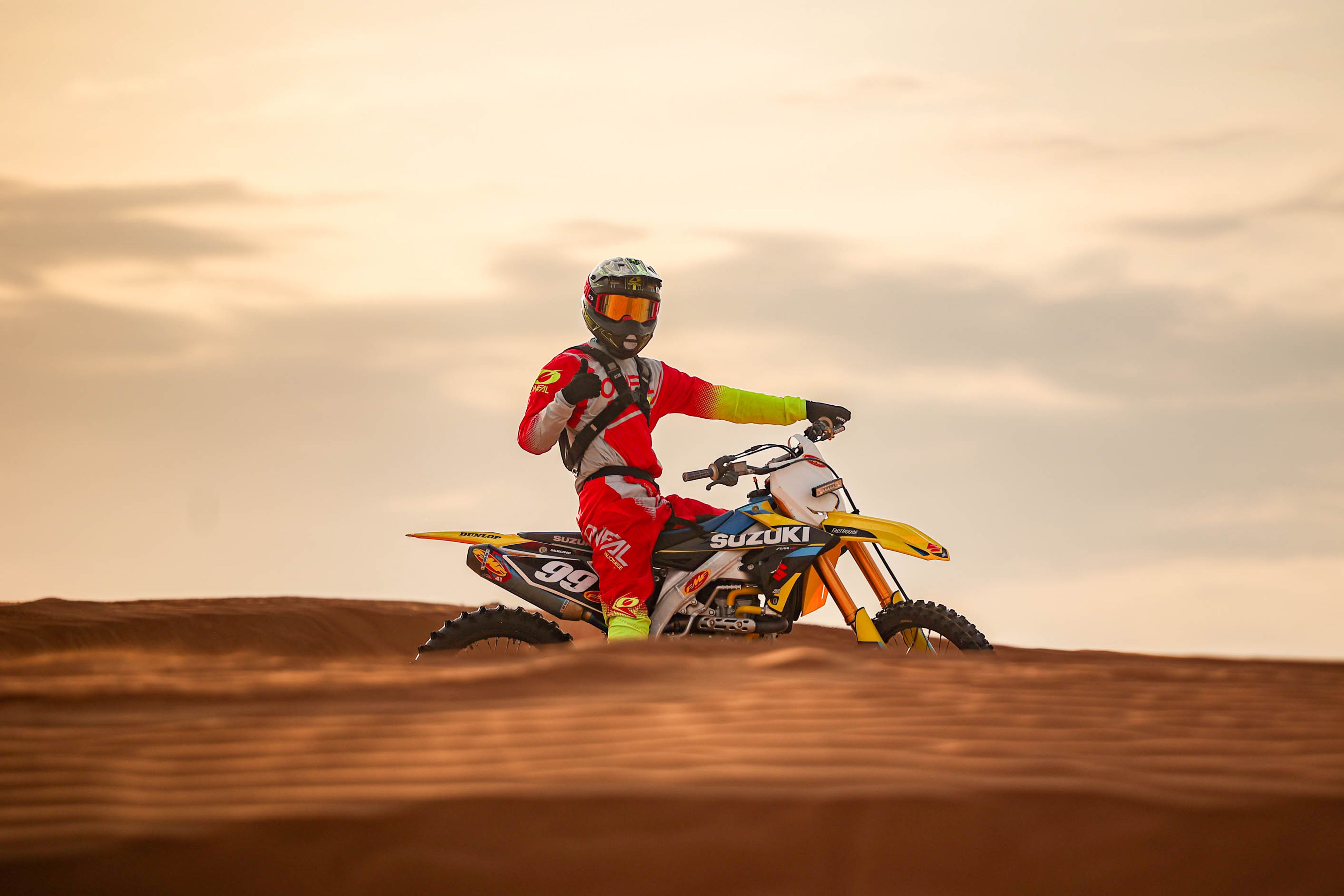 Motocross rider on sand dunes at sunrise, showcasing an adventurous spirit.
