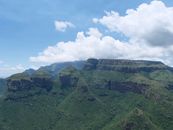 A stunning aerial view of the lush green Blyde River Canyon under a bright blue sky.