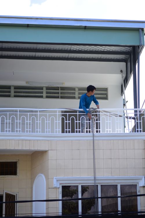 Free Man in blue shirt working on a balcony of a building outdoors, conveying urban lifestyle. Stock Photo