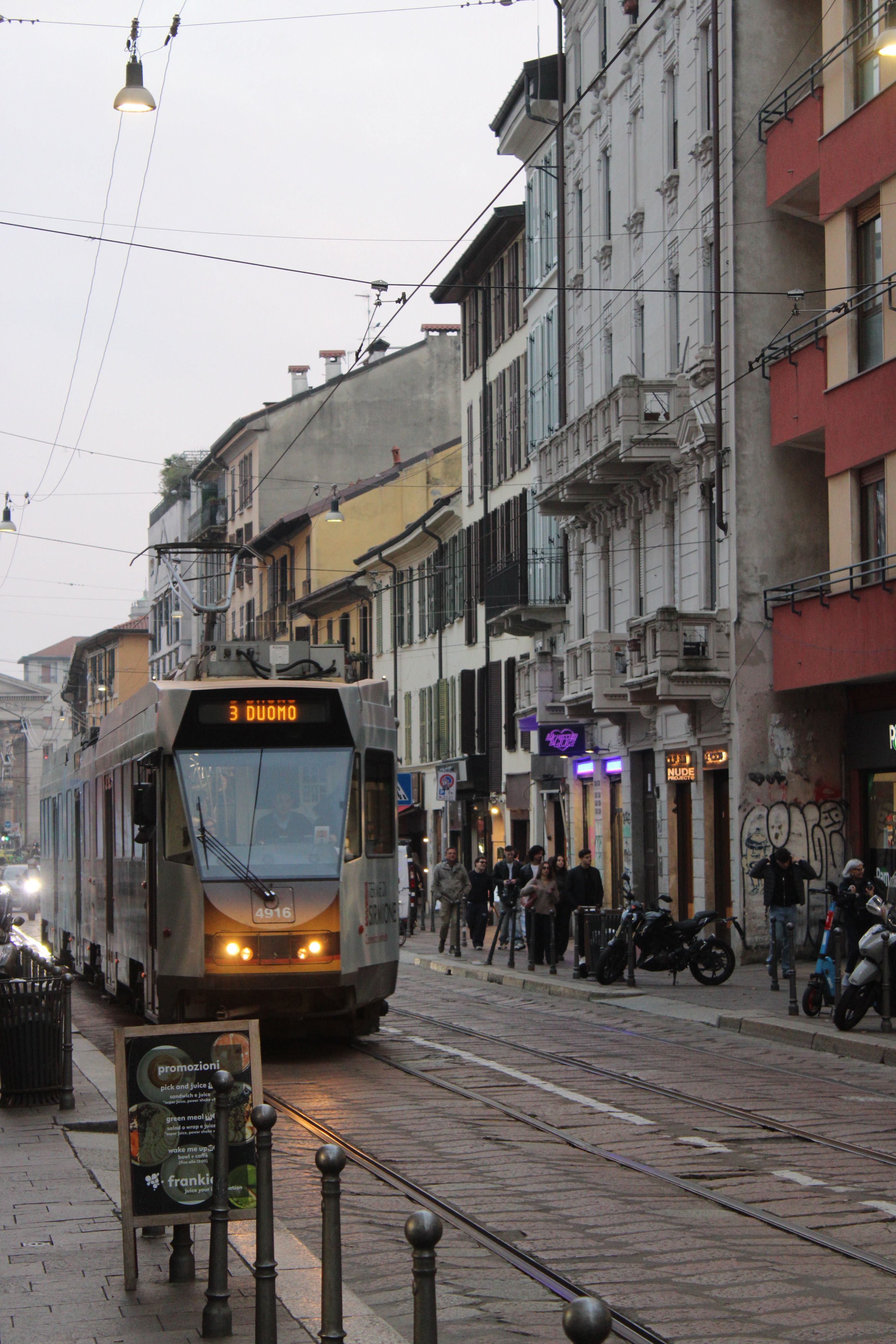 A bustling street scene in Milan featuring a tram and classic European architecture.