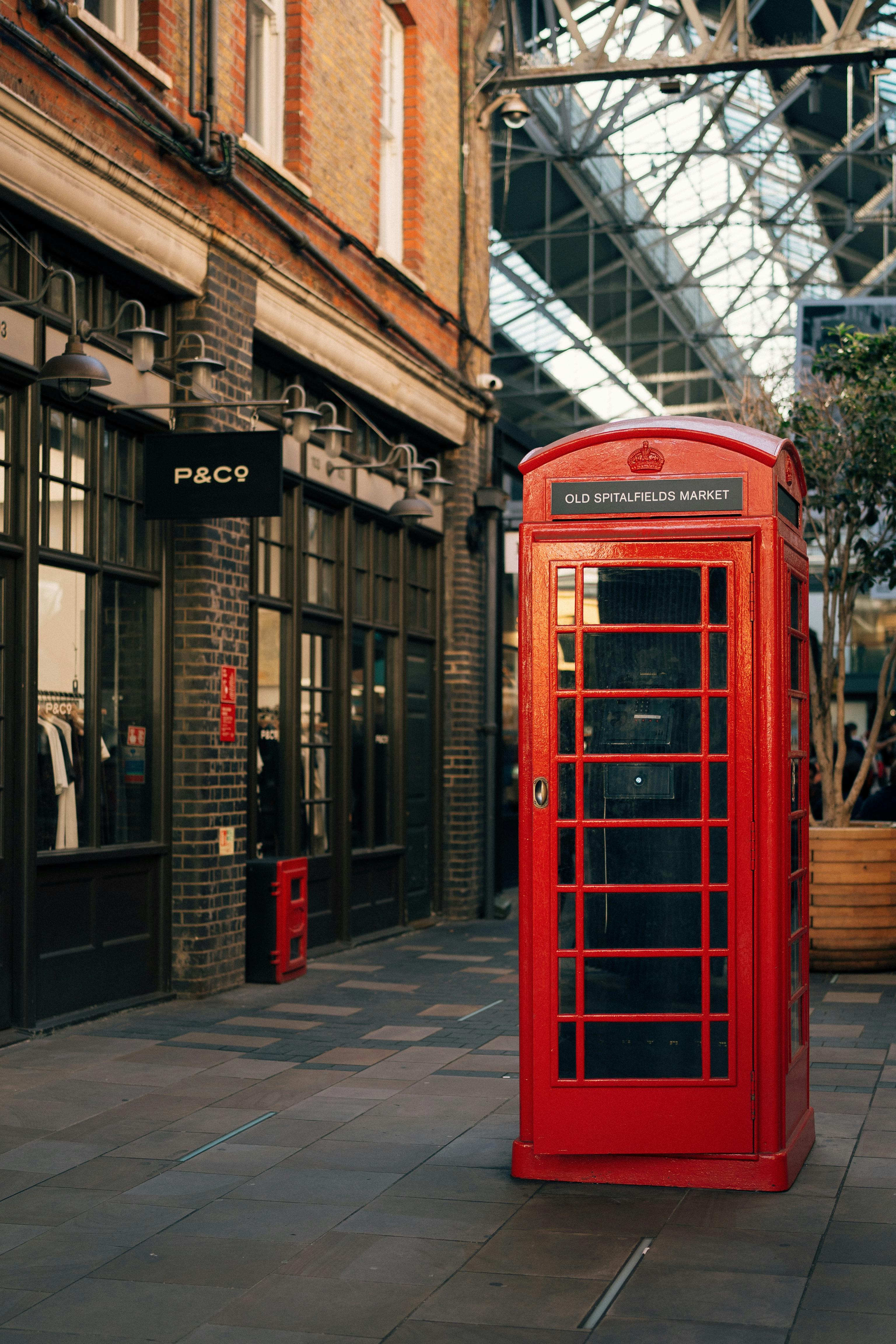 Classic red phone booth at Old Spitalfields Market, capturing London's historic charm in a modern setting.