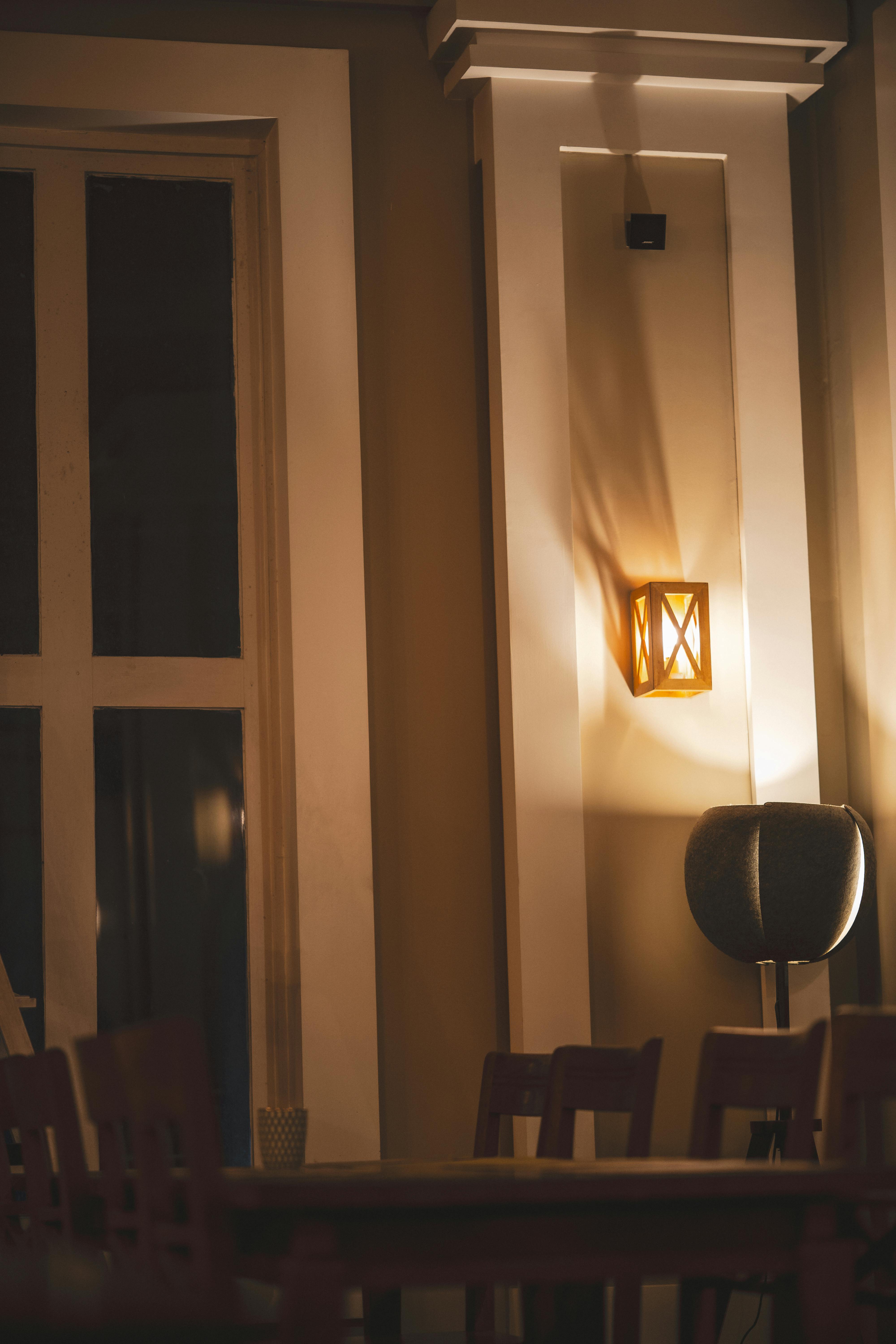 De franc Interior de cafeteria càlidament il·luminat amb un aplic rústic i una disposició de seients acollidora, perfecte per a una vetllada tranquil·la. Foto d'estoc