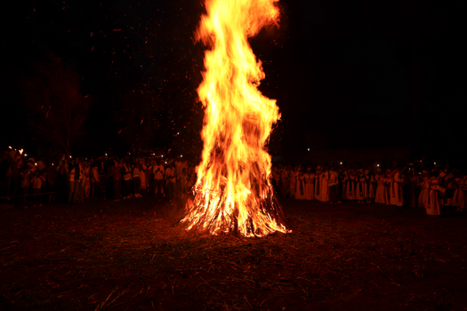 Nighttime Ethiopian Orthodox celebration with a large bonfire and people in traditional attire.