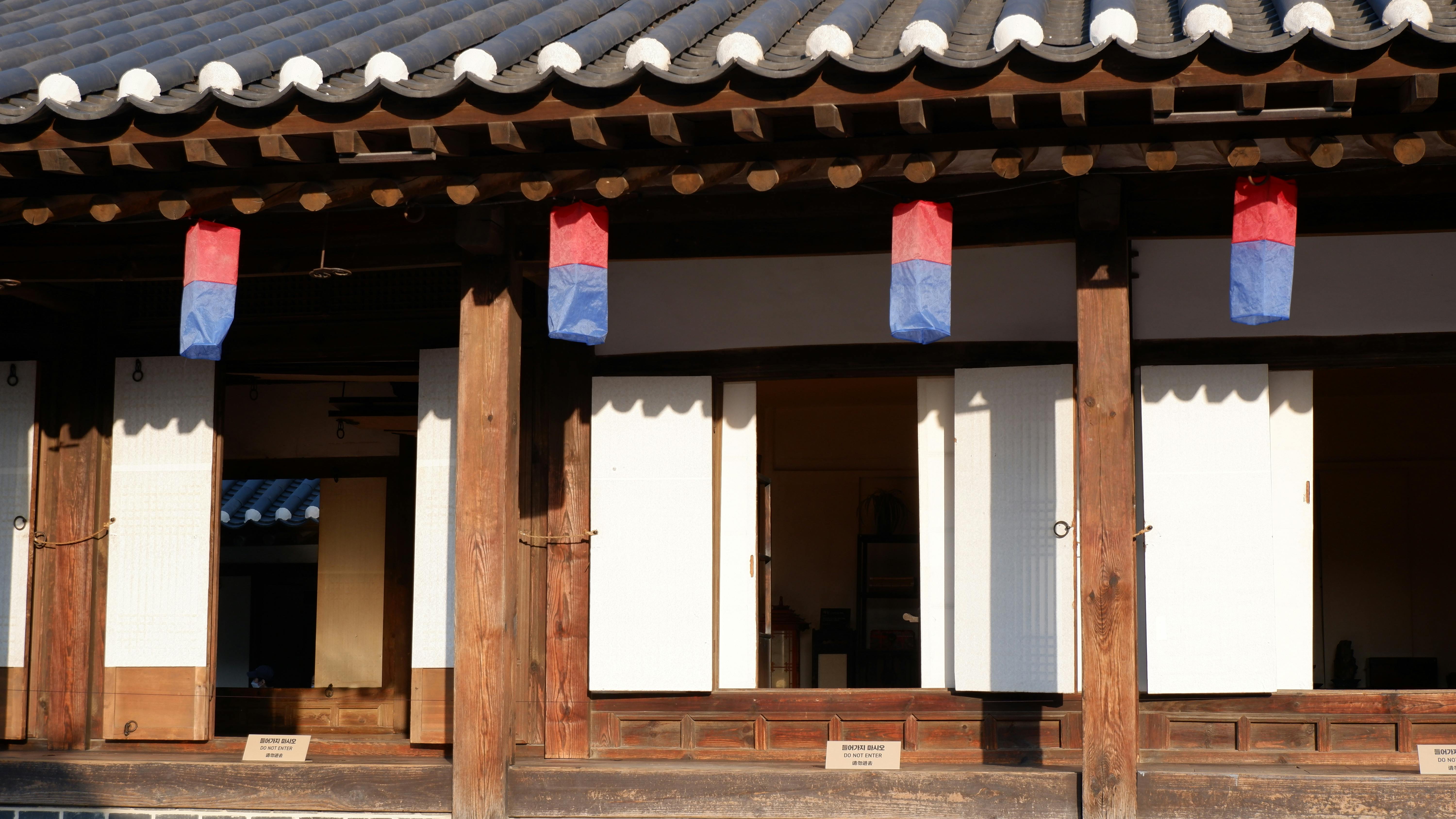 A scenic view of a traditional Korean Hanok with vibrant red and blue lanterns.
