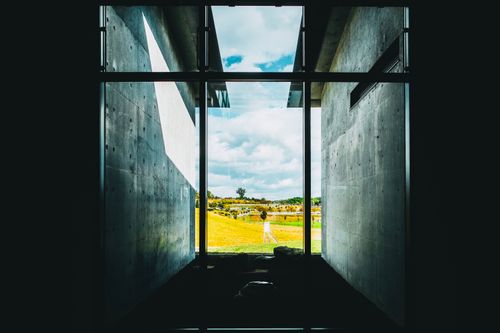 Free View through modern architecture window framing an open field under a blue sky. Stock Photo