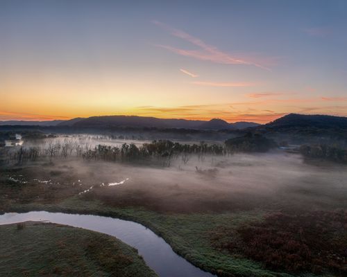 Free A picturesque sunrise over a misty river valley in Tell, Wisconsin, capturing nature's serene beauty. Stock Photo