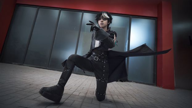 A young adult in striking cosplay attire poses dramatically indoors, embodying fantasy and role-playing themes.
