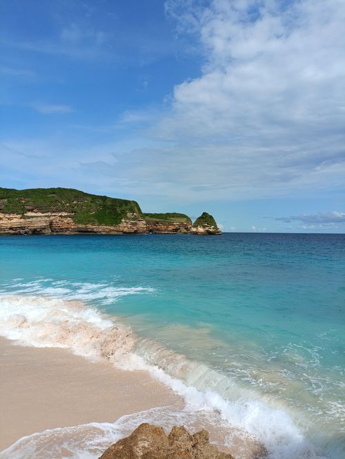 Free Stunning view of a serene beach in West Nusa Tenggara, with clear turquoise waters and lush cliffs. Stock Photo