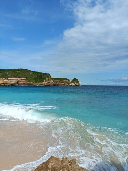 Free Stunning beach with turquoise waters and rocky cliffs under a bright sky. Stock Photo