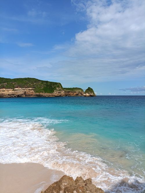 Free Peaceful tropical beach with turquoise ocean and rocky landscape under a blue sky. Stock Photo