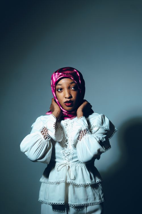 Free Elegant studio portrait of a woman wearing a pink headscarf and white traditional dress. Stock Photo