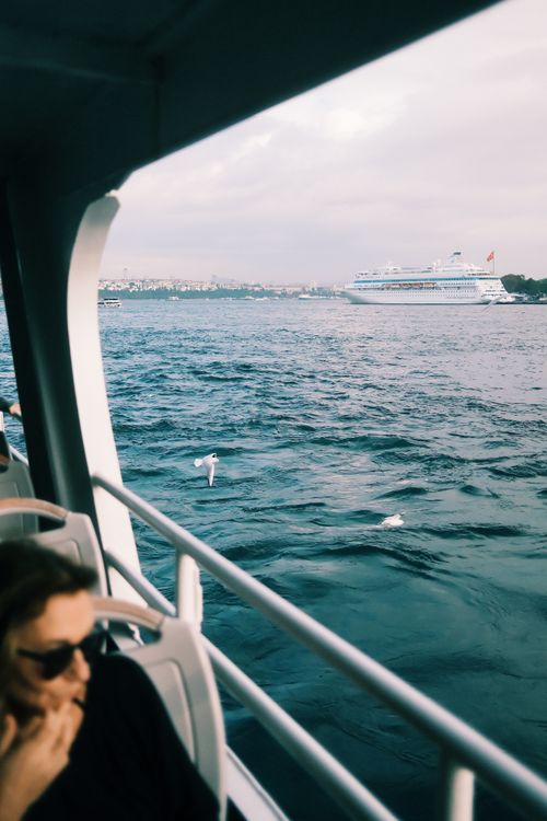 Free A passenger enjoys a scenic cruise with a ship in the distance on a serene waterway. Stock Photo