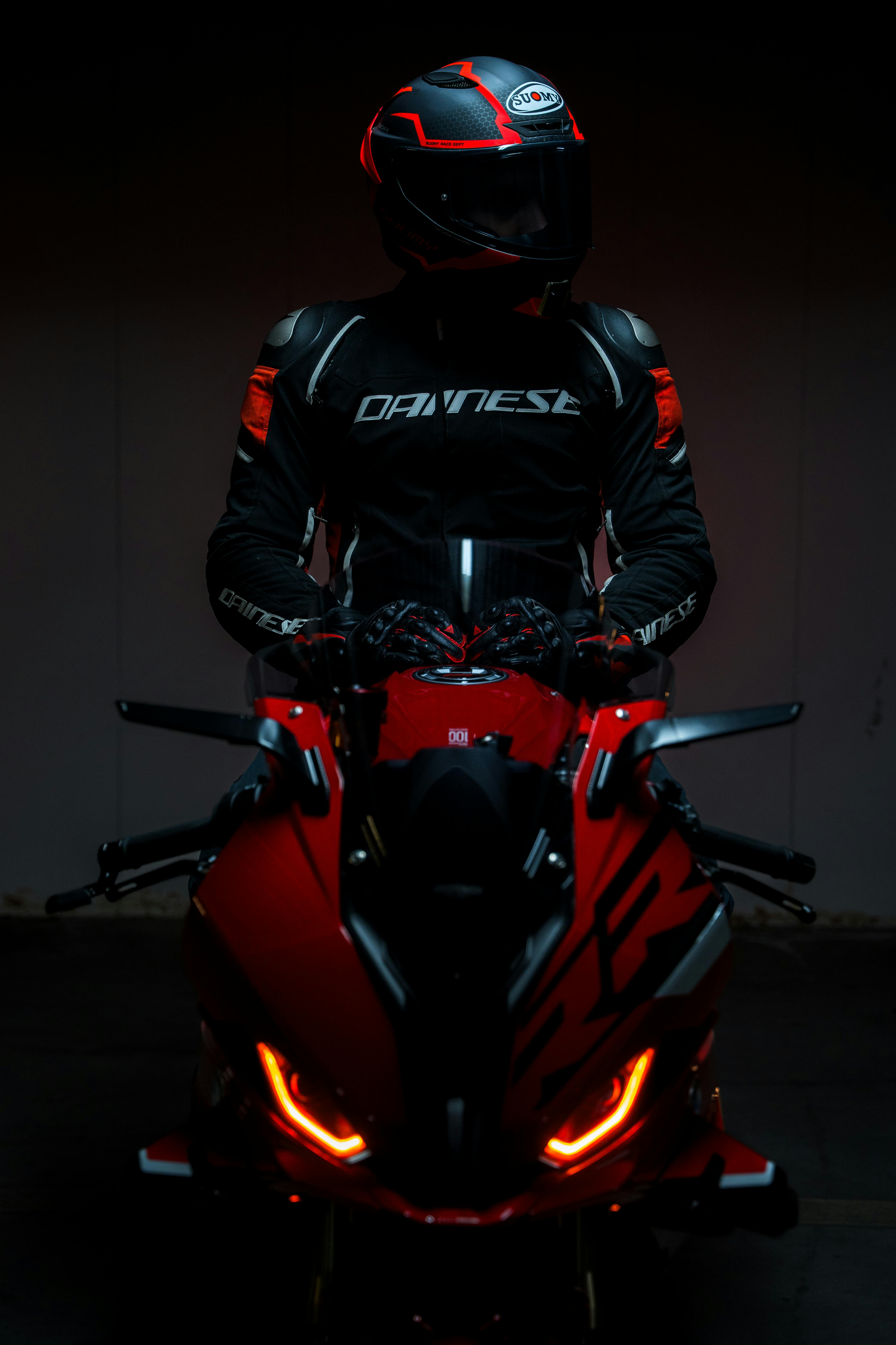 motorcyclist in black gear on red bike