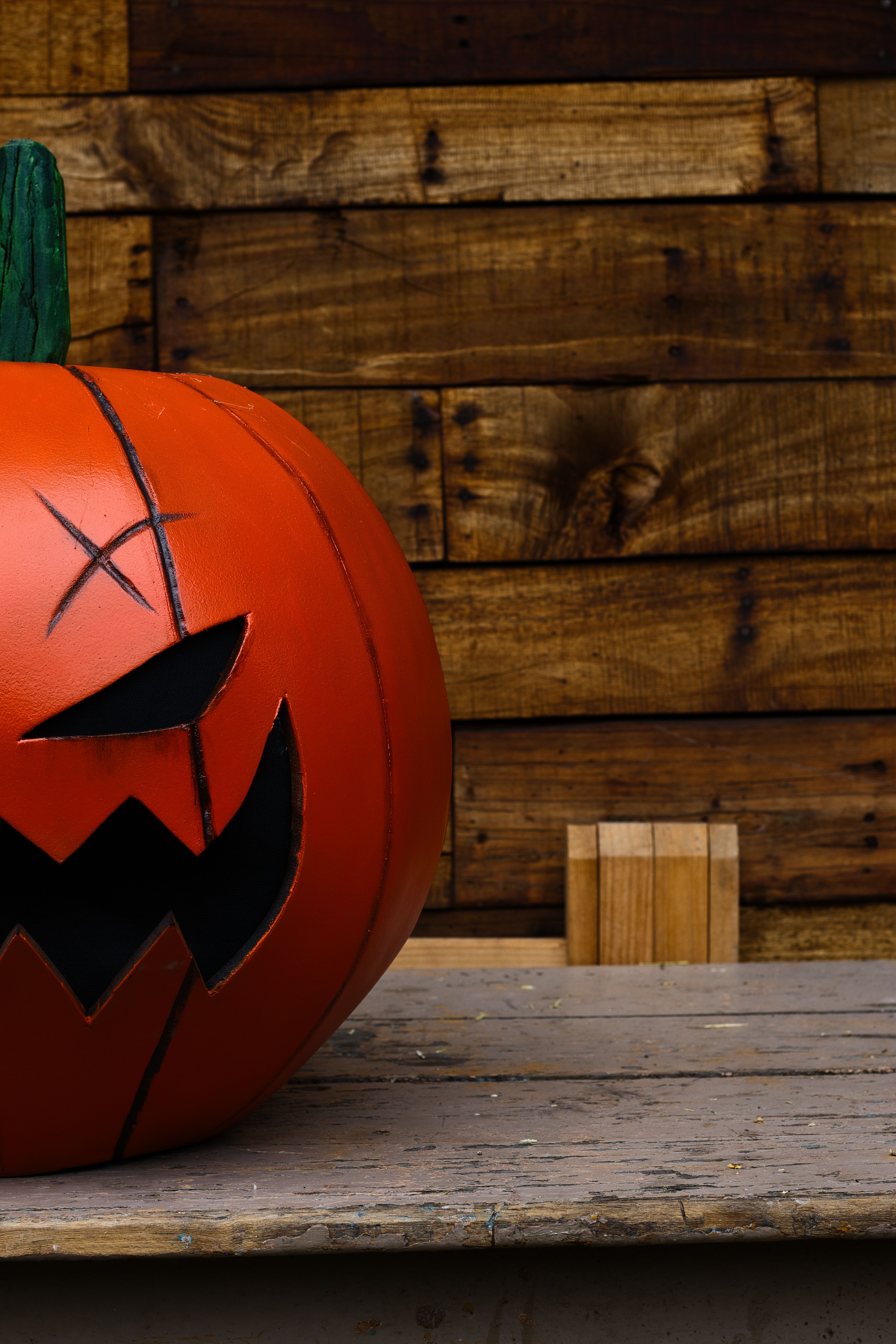 Jack-o'-Lantern with carved face sits on a rustic wooden table, perfect for Halloween decor.