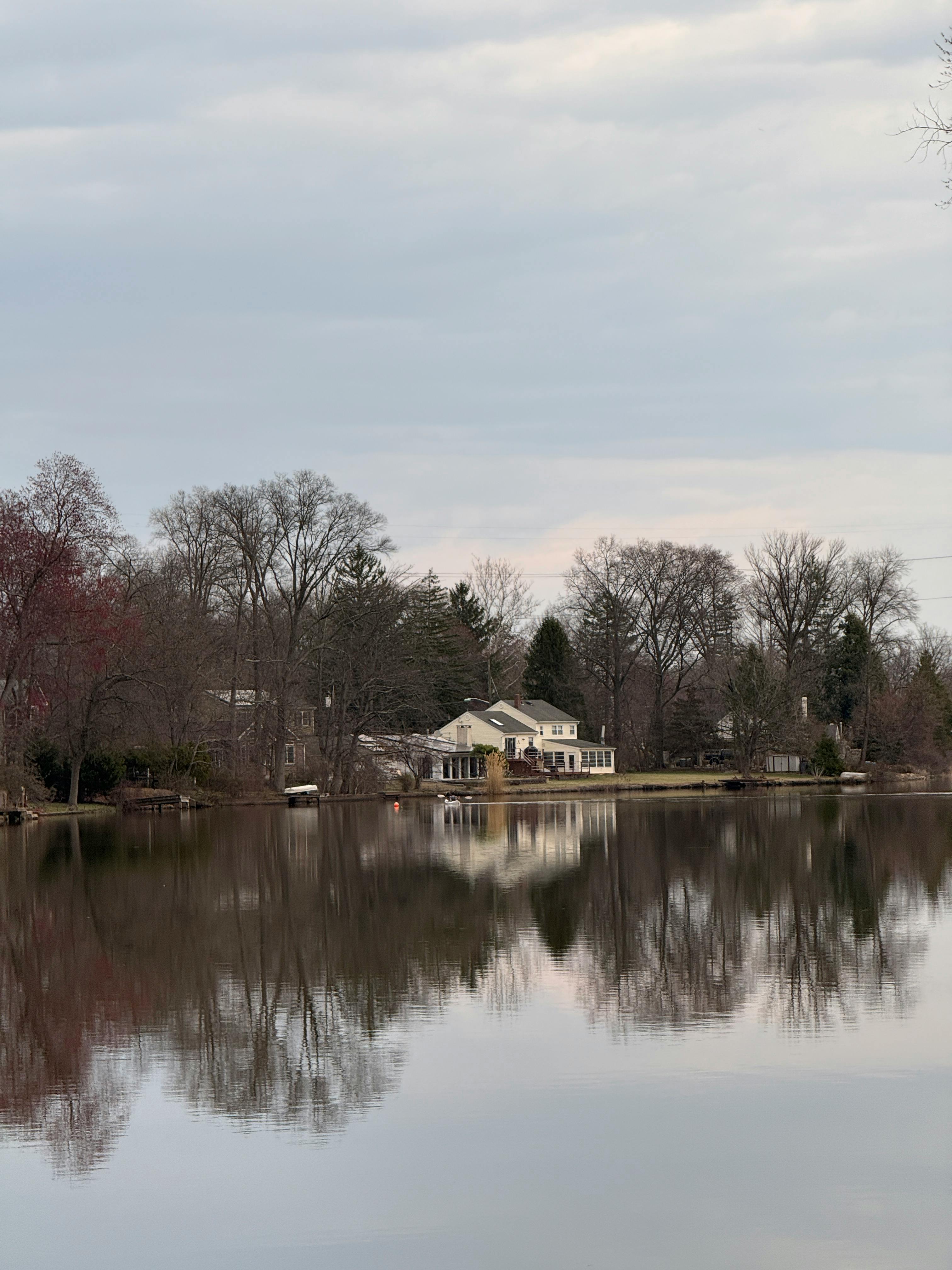 Charming lakeside house with autumn trees reflecting in tranquil water. Captured in New Jersey.