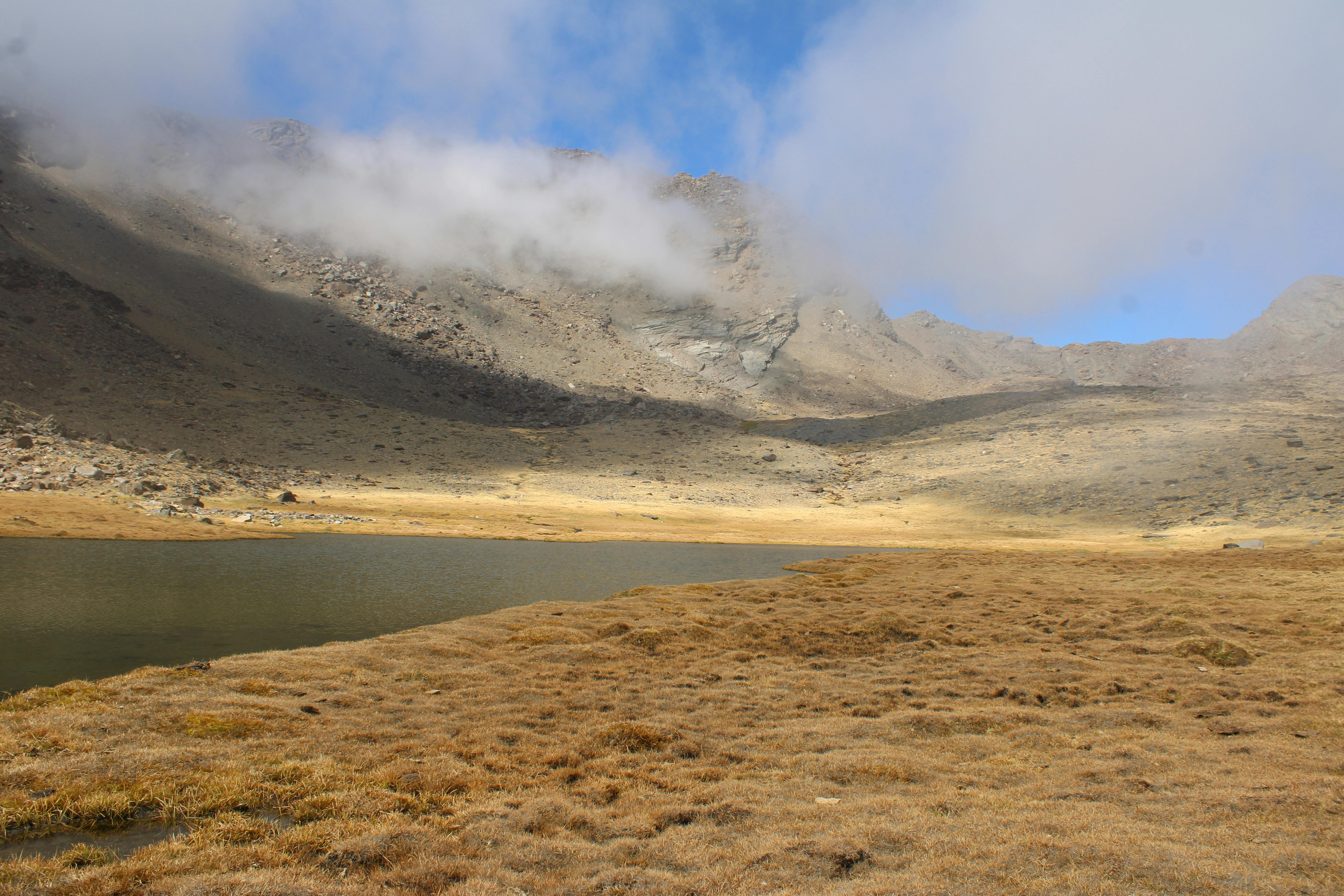 Breathtaking view of an alpine lake surrounded by misty mountains in Trevélez, Sierra Nevada.