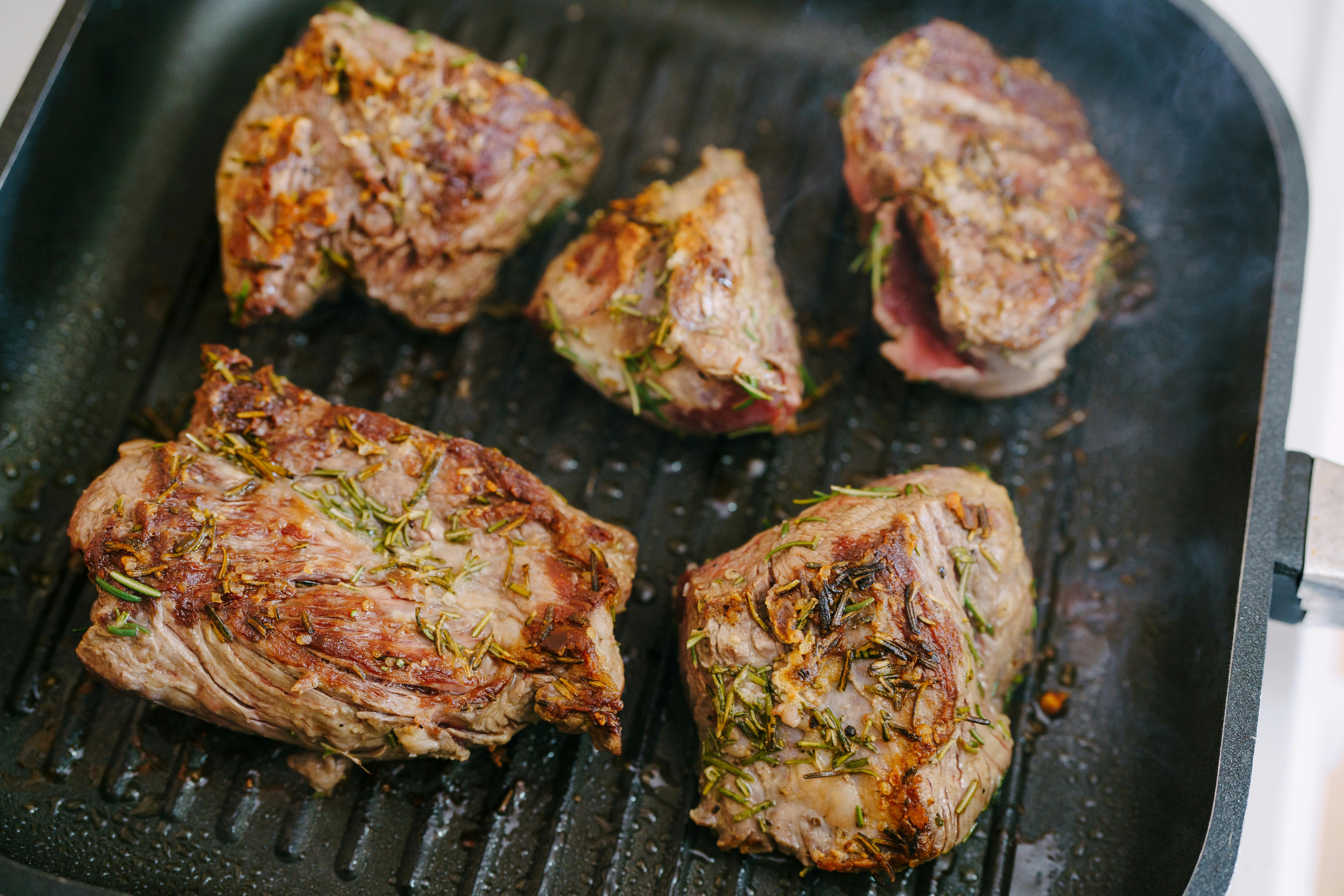 Deliciously seasoned lamb chops roasting with herbs in a grill pan.