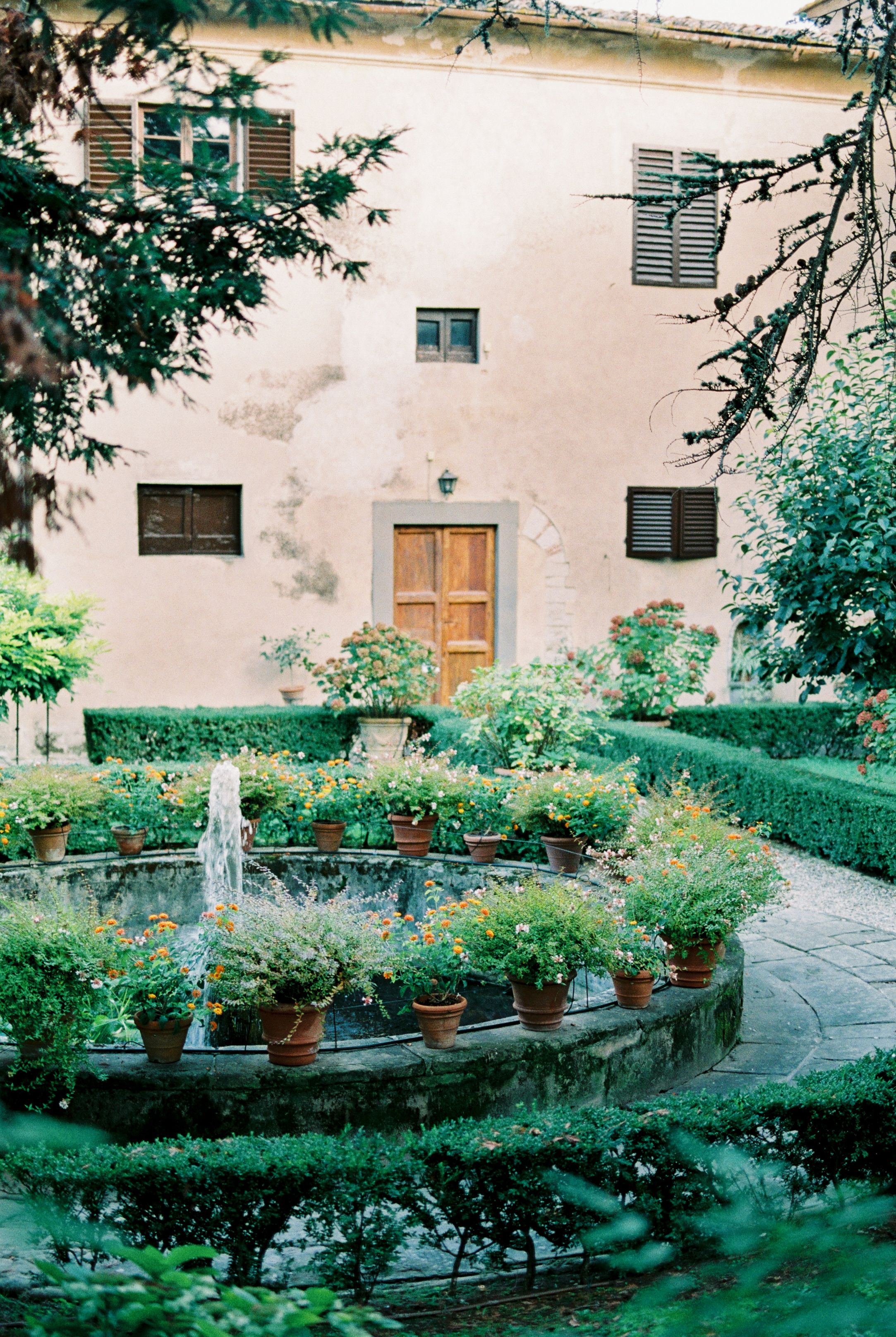 Serene courtyard garden with vibrant plants surrounding a classical fountain.