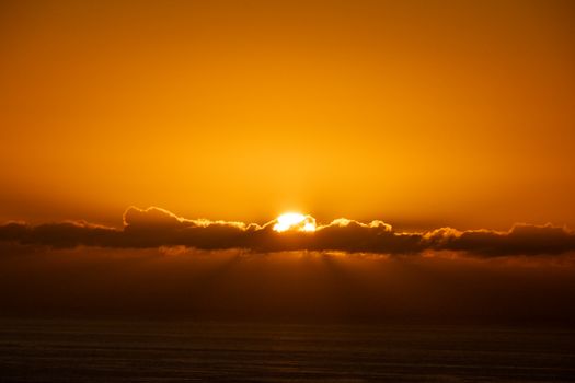 A stunning sunset over the ocean in Cape Town, South Africa, with golden clouds and serene waters.