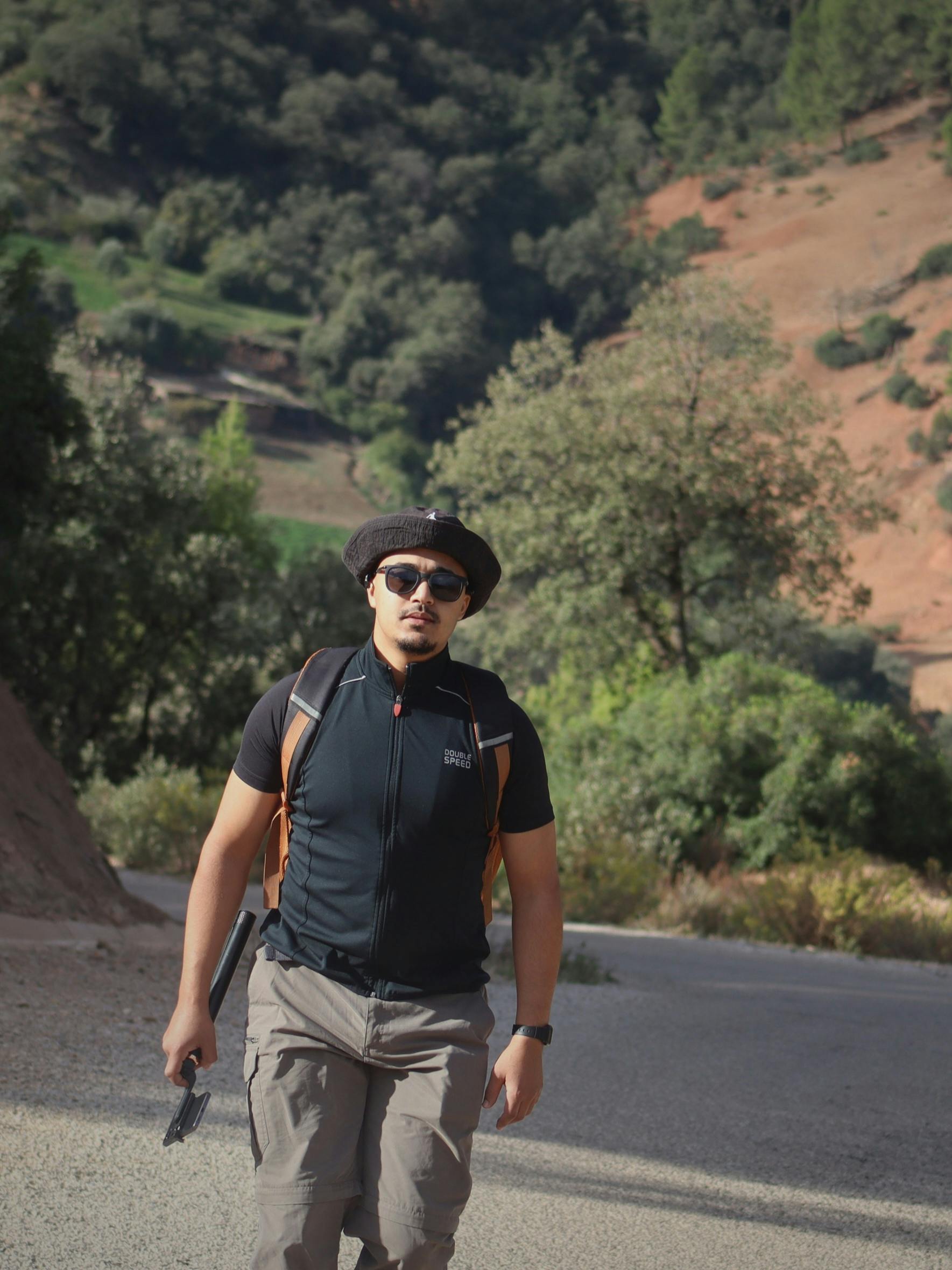 Outdoor enthusiast hiking on a mountain trail surrounded by lush greenery and clear skies.