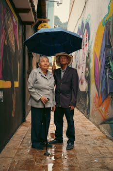 Charming portrait of a senior couple sharing an umbrella in a colorful Bogotá alley.