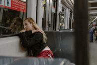 A woman lost in thought, resting against a Barcelona metro window, conveys urban solitude.