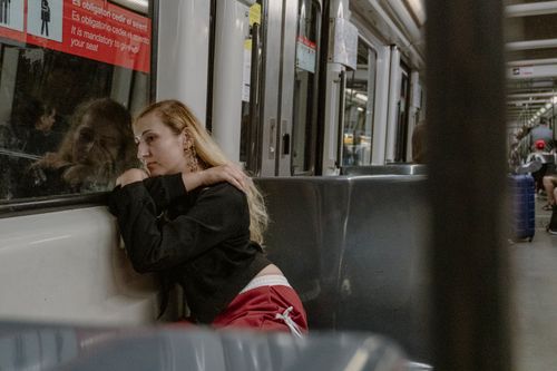 Free A woman lost in thought, resting against a Barcelona metro window, conveys urban solitude. Stock Photo