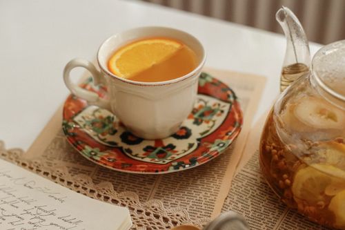 Free A vintage tea set with citrus infused tea on a lace-covered table, creating a warm and inviting atmosphere. Stock Photo