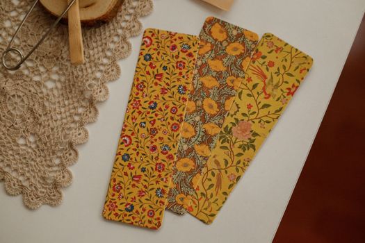 Three vibrant floral-patterned bookmarks placed on a lace doily, showing intricate designs.