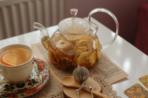 Free A cozy setting featuring a glass teapot with herbal tea and a cup on a floral saucer. Stock Photo