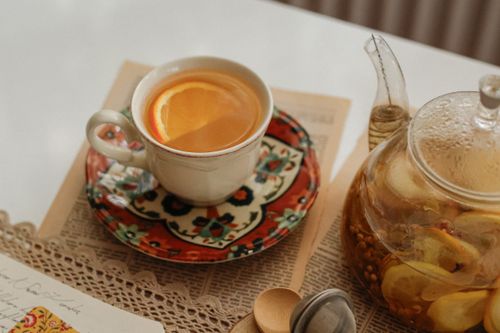 Free A warm cup of herbal citrus tea and teapot in a charming vintage setup. Stock Photo