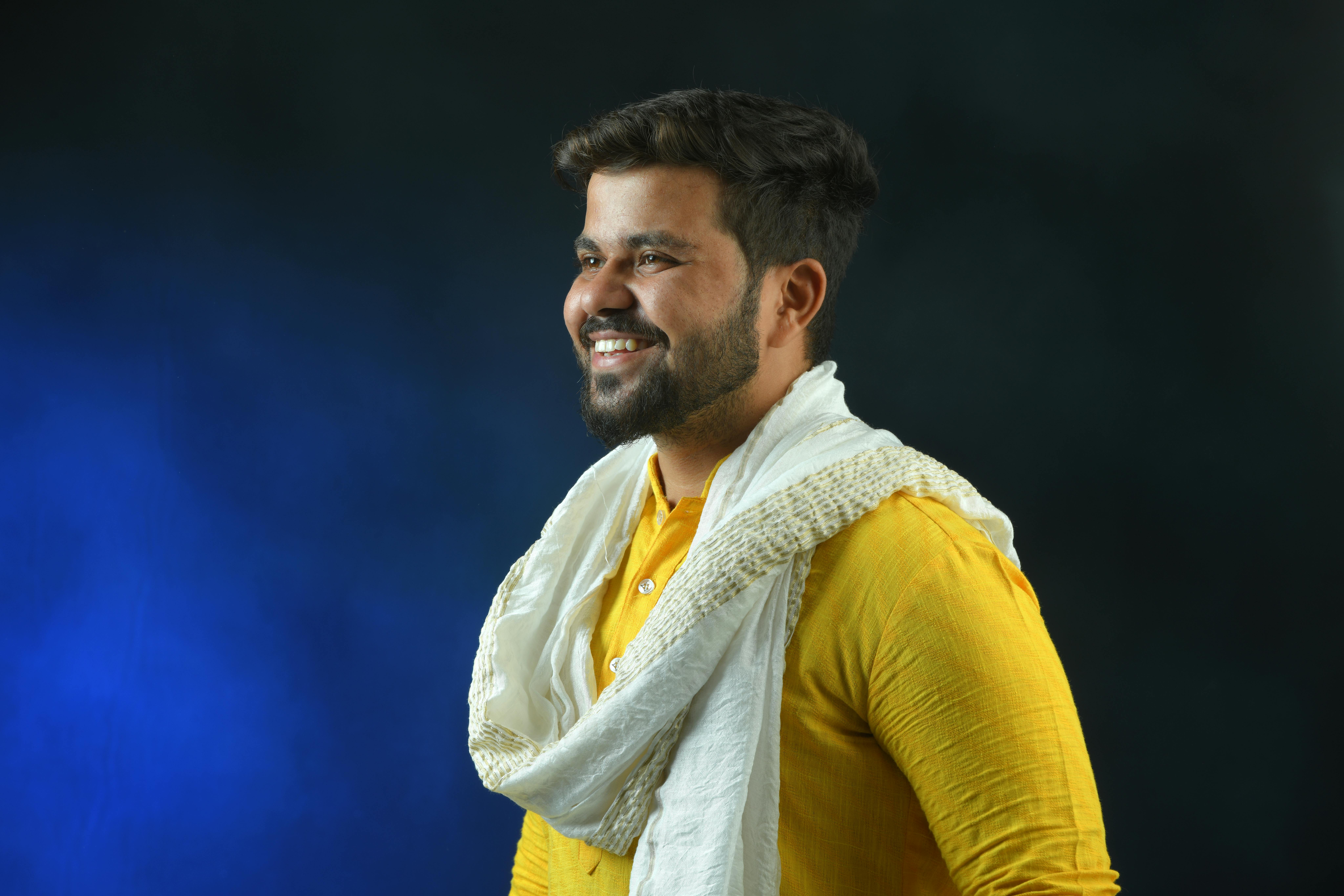 Portrait of a smiling man in a vibrant yellow kurta and white scarf, showcasing traditional Indian style.