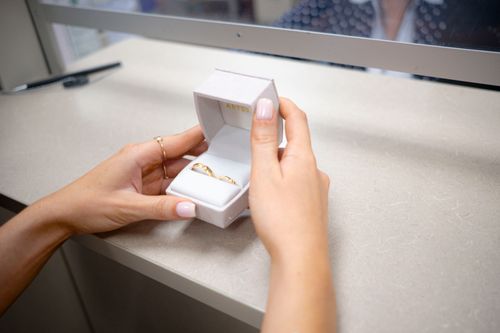Free Close-up of hands opening a box with wedding rings at a store counter. Stock Photo