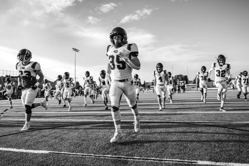 Free High school football team practicing on a field, showcasing energy and teamwork in a black and white photo. Stock Photo