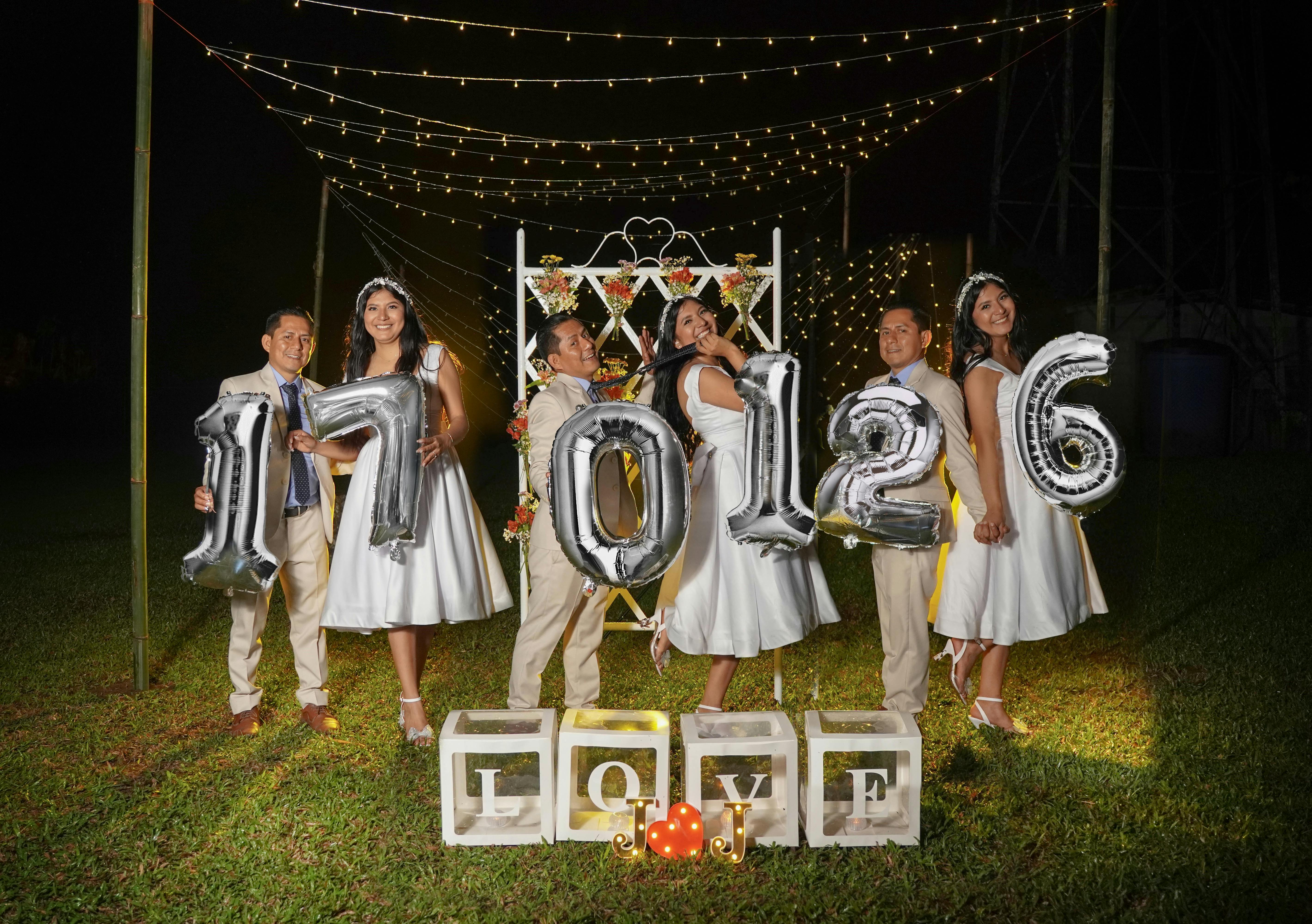 Group photo of a wedding party with balloons and fairy lights in Santo Domingo, Ecuador.